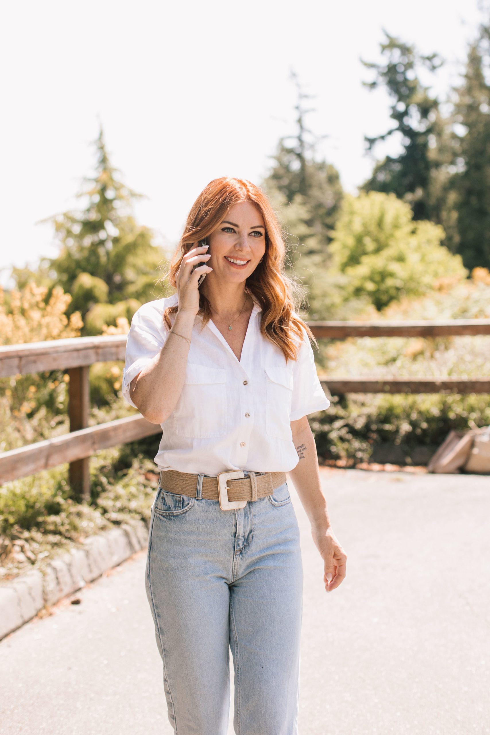 A woman in white shirt holding a cell phone.